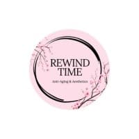 Pink circular logo for Rewind Time Anti-Aging & Aesthetics with a cherry blossom branch design.